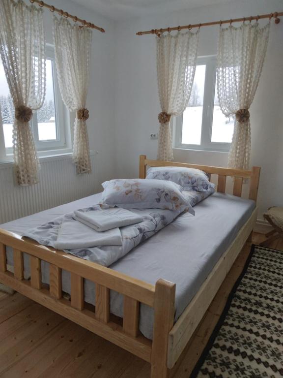 a bedroom with a wooden bed with pillows on it at Casa din Deal-Apuseni in Ocoale