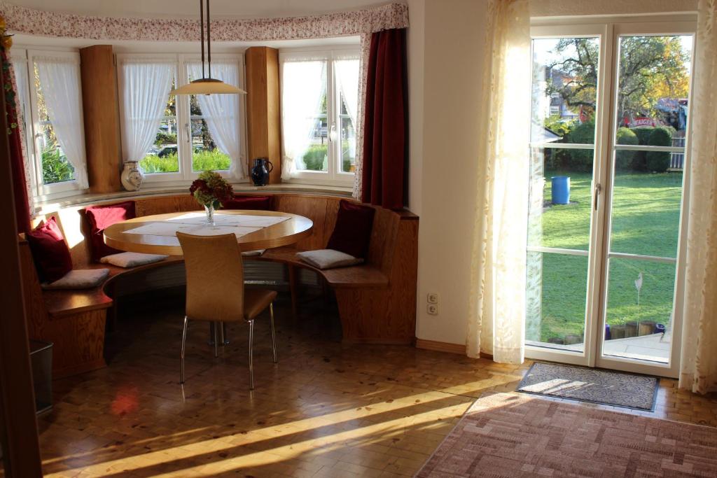 een eetkamer met een tafel en een aantal ramen bij Ferienwohnung Erhard in Prien am Chiemsee
