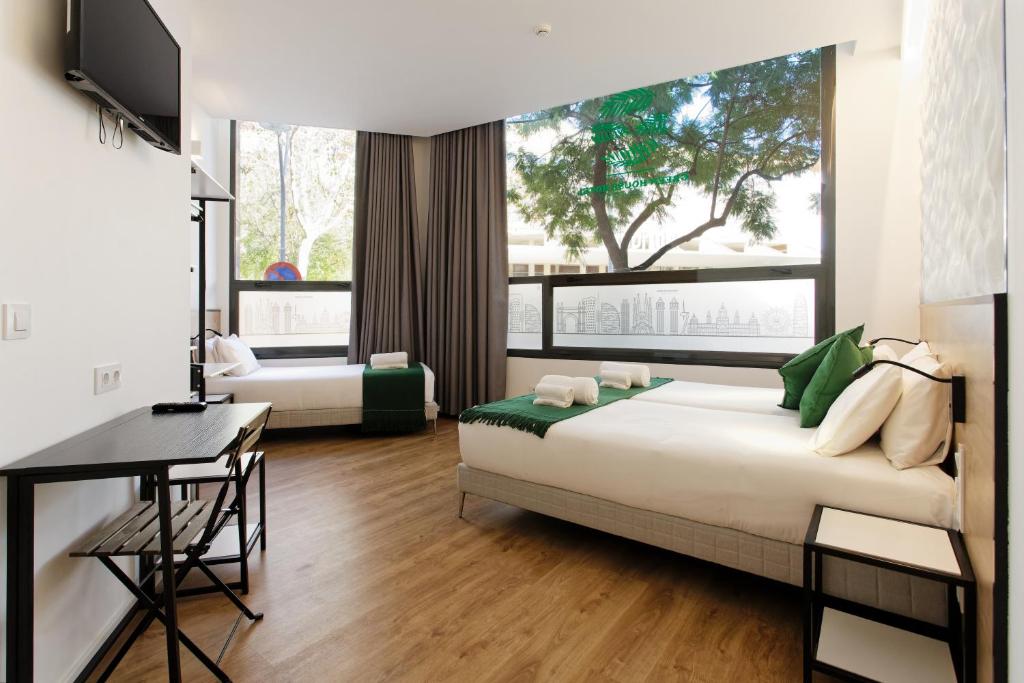 a bedroom with a bed and a desk and a window at Green House Hotel in Barcelona