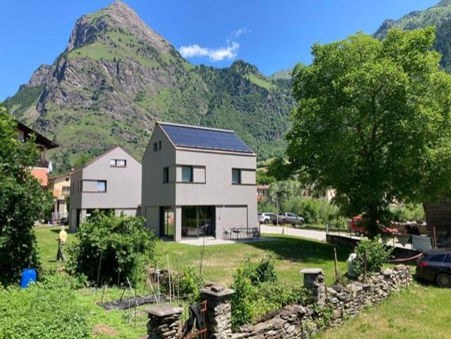 uma casa em frente a uma montanha com um carro em Ca' dal Nos em Olivone