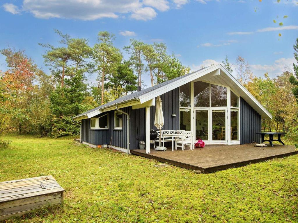 a black cottage with a deck and a table at 8 person holiday home in Grenaa in Grenå
