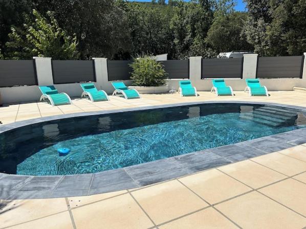 a swimming pool with blue chairs and a group at VILLA AVEC PISCINE in Néoules