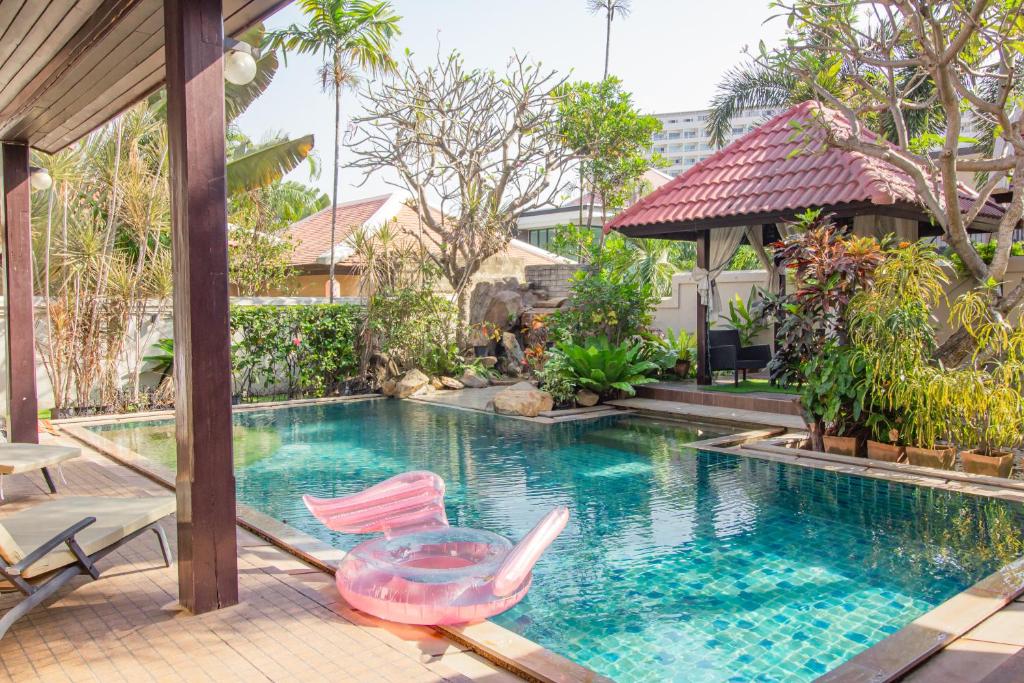 una piscina con 2 sillas y una mesa junto a una casa en Bali Haven 3BR PrivatePool Villa en Pattaya South