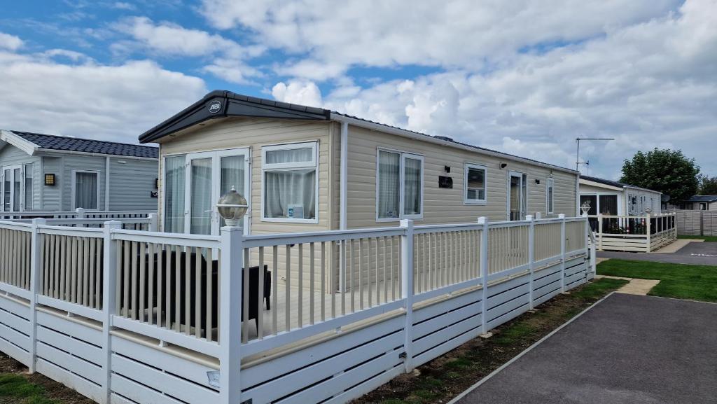 a mobile home with a white fence at Rye Harbour Holiday Park in Rye Harbour
