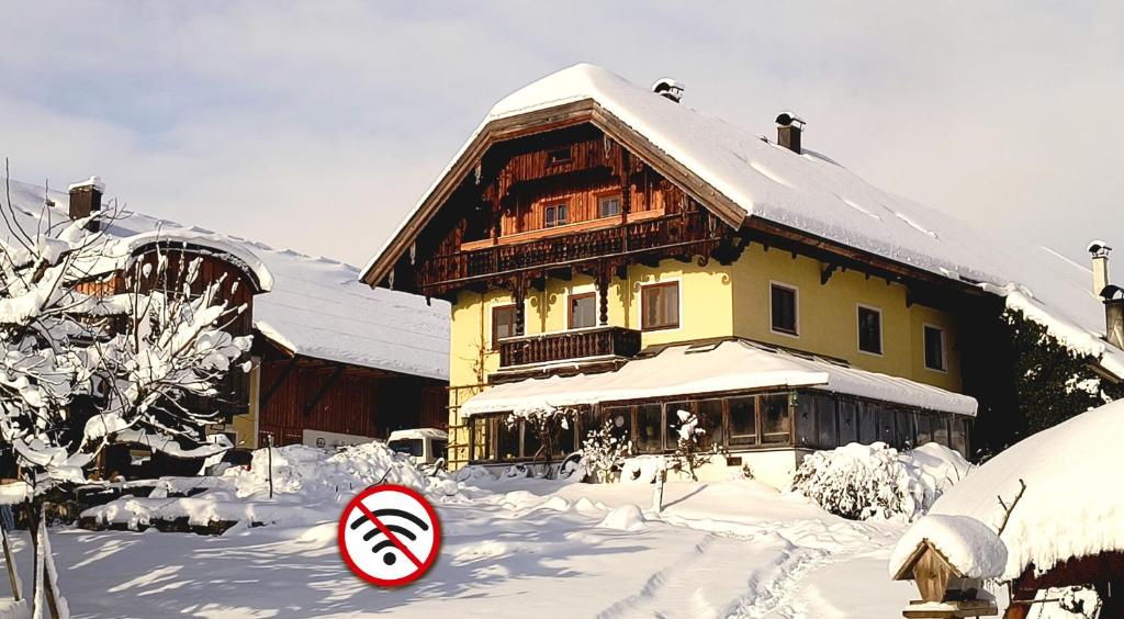 a snow covered house with a sign in front of it at Bio Archehof Zachhiesen - stay & relax in Seekirchen am Wallersee
