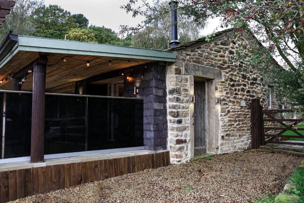 ein Steinhaus mit einer Glastür und einem Zaun in der Unterkunft Tanyard Barn - Luxury Hot Tub & Secure Dog Field Included in Old Glossop