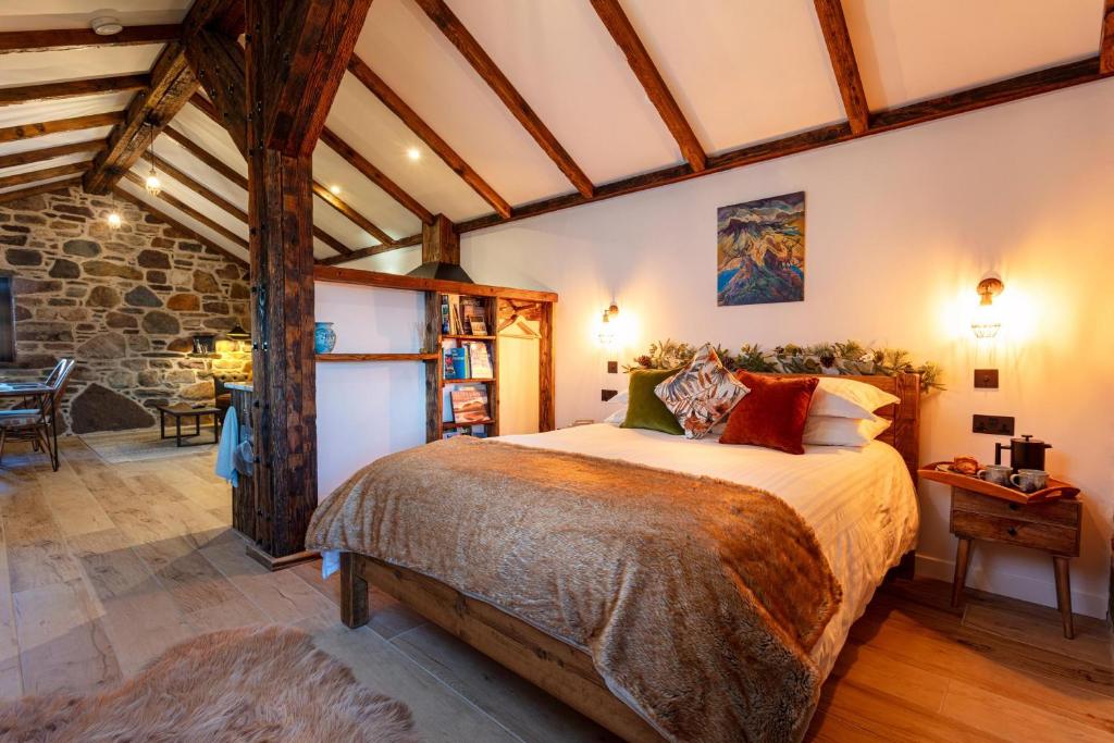 1 dormitorio con 1 cama grande y pared de piedra en The Ruin - Lochside Cottage dog friendly, en Ullapool