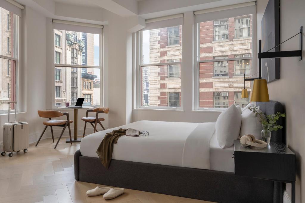 a bedroom with a bed and a desk and windows at Sonder Flatiron in New York