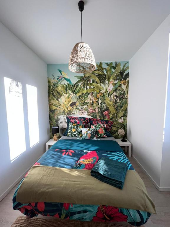 a bedroom with a bed with a tropical wallpaper at Studio tropical , vierzon , proche gare , tout confort in Vierzon