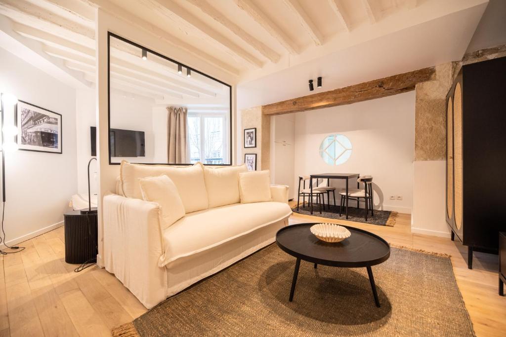 un salon avec un canapé blanc et une table dans l'établissement Cosy Nest in Saint Germain, à Paris