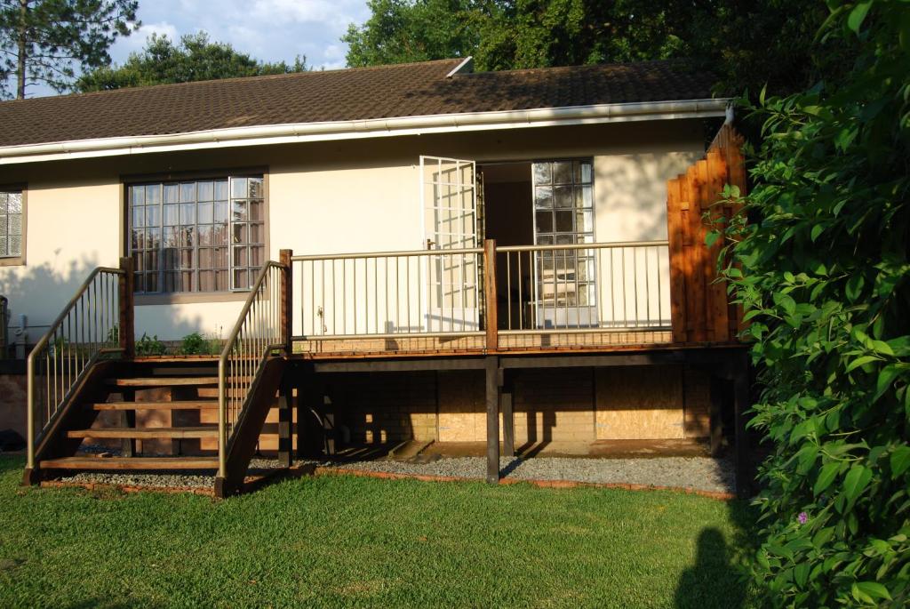 a house with a deck and stairs in the yard at Urban Bush Lodge in Howick