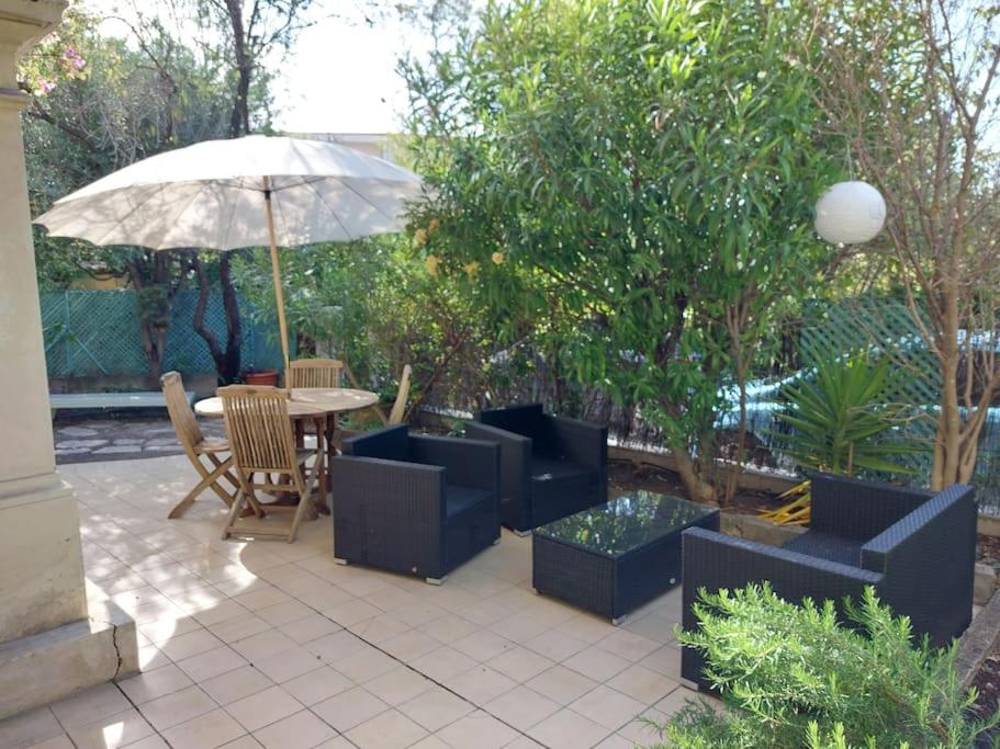 un patio avec une table, des chaises et un parasol dans l'établissement Heliotropes T3 avec terrasse -Axelle Loc'Appart, au Cannet