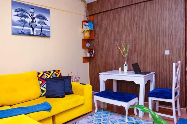 sala de estar con sofá amarillo y mesa con ordenador portátil en Naivasha 2 Bedroom Rated Best, en Naivasha