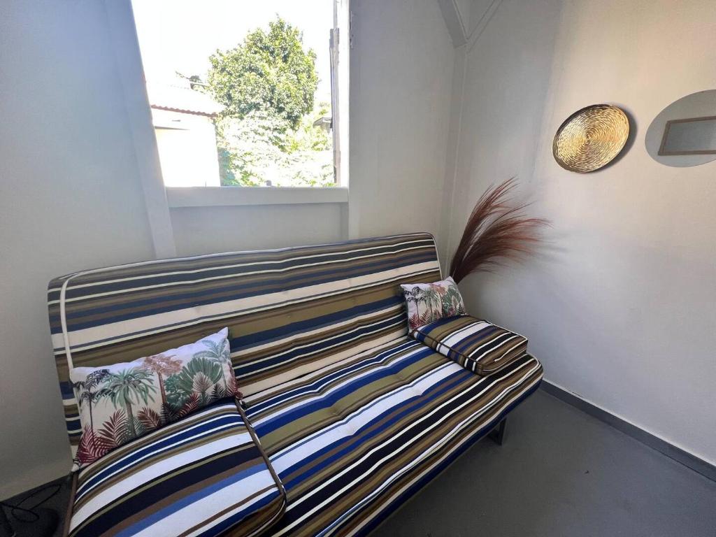 a couch sitting in a room with a window at Bonheur en Centre-Ville : Réservez votre Évasion F2 à Basse-Terre in Basse-Terre