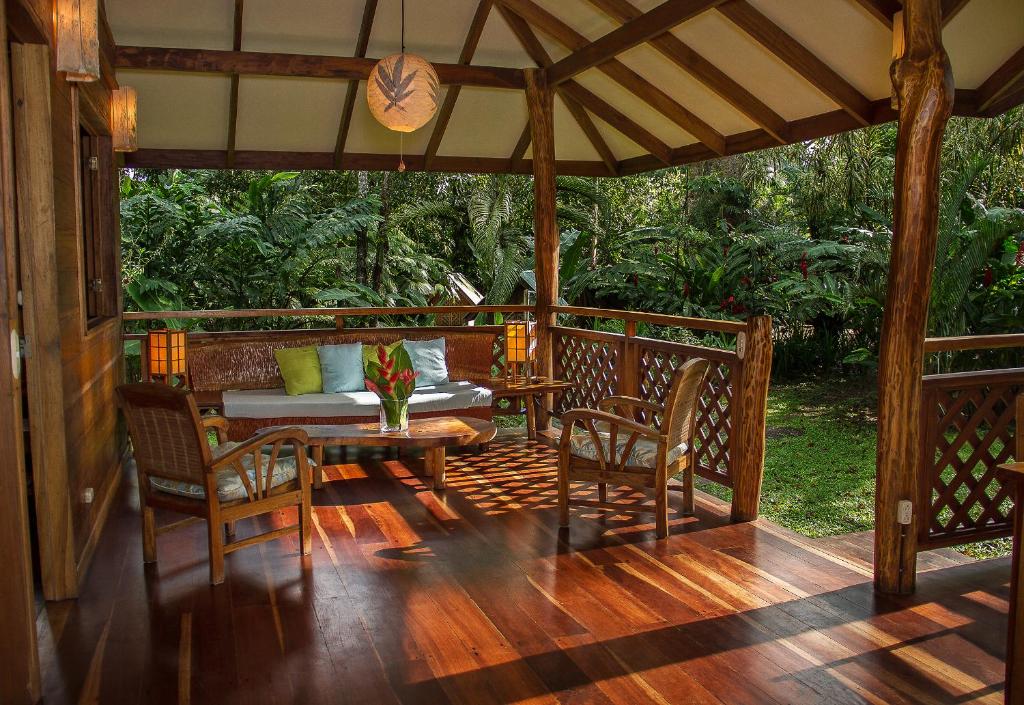 un porche de madera con mesa y sillas. en Finca Chica Lodge & Villas, en Puerto Viejo