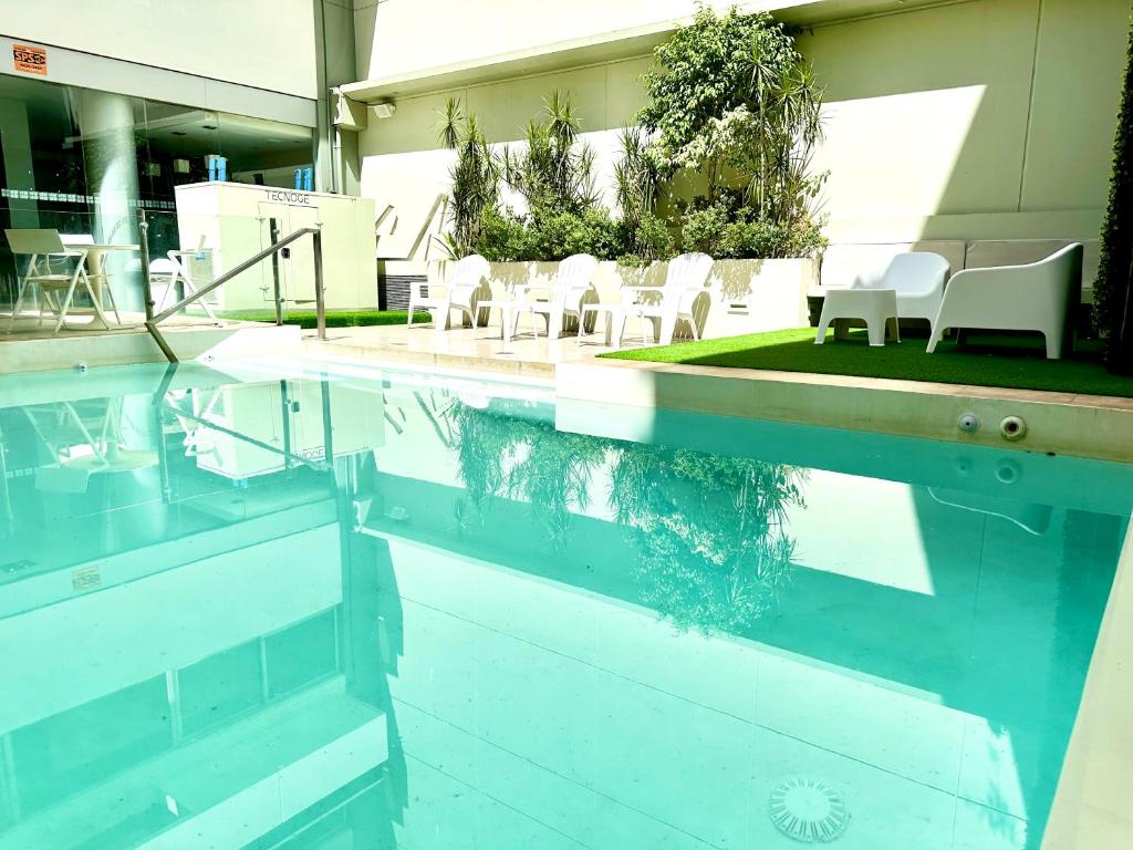 una piscina de agua con sillas y mesas blancas en Guido 1980 by Ayres Apartments Recoleta, en Buenos Aires
