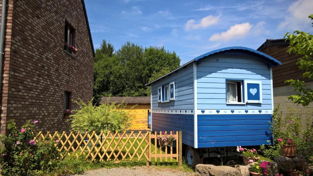un cobertizo azul en un patio junto a un edificio en The Little Blue Caravan en Scy