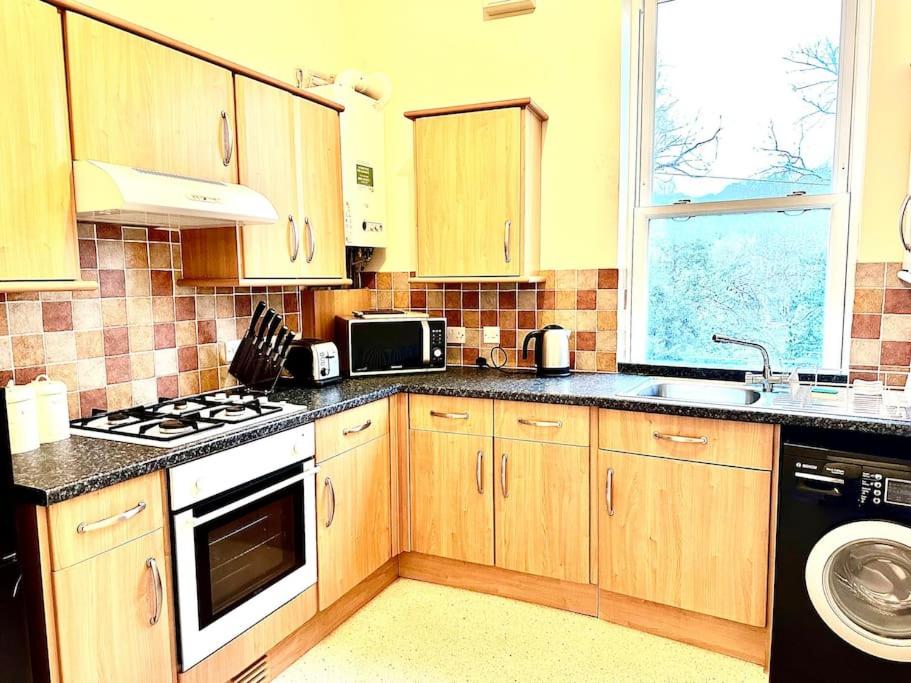 a kitchen with wooden cabinets and a stove top oven at Relaxing Park View Apartment in Hastings
