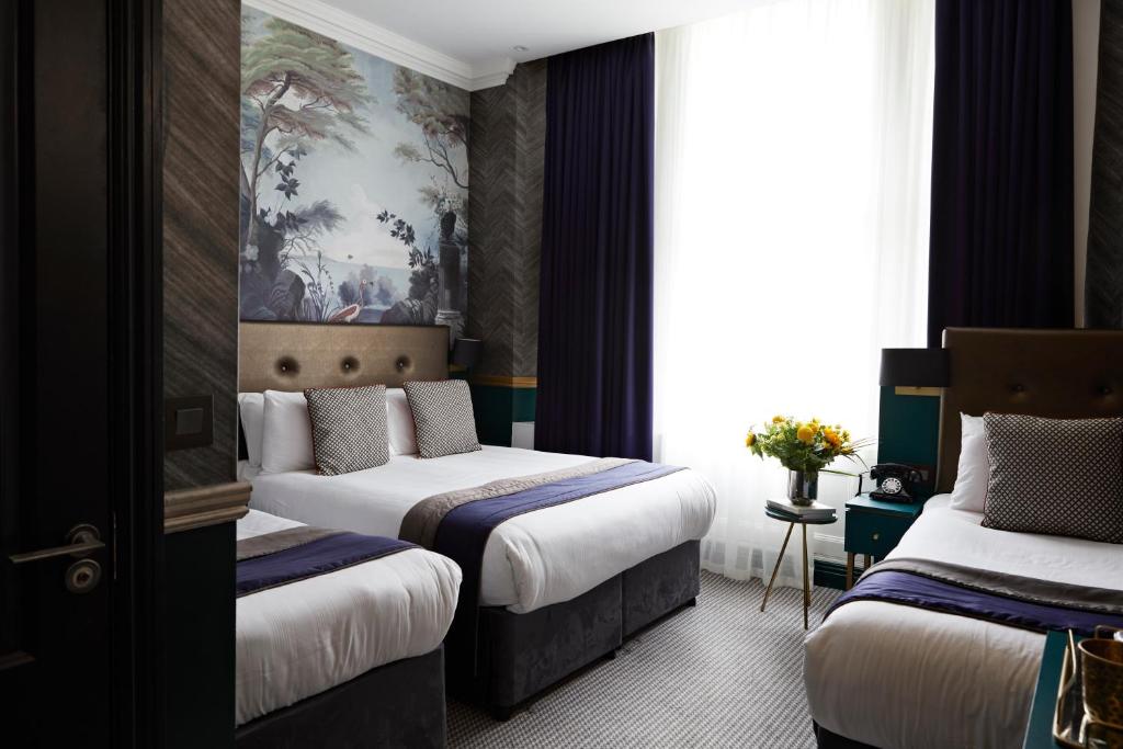 a hotel room with two beds and a painting on the wall at The Portico Hotel in London