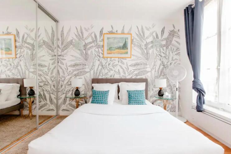 una camera da letto con un letto bianco con cuscini blu di Le Studio Versaillais a Versailles