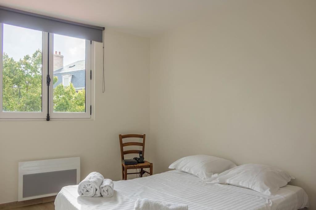 a white bedroom with a bed and a window at Les Augustins *T4* in Orléans