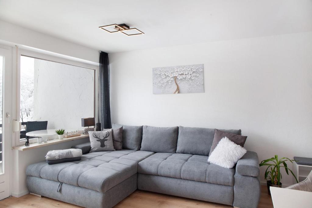 uma sala de estar com um sofá cinzento e uma janela em Ferienwohnung Bergblick em Buching