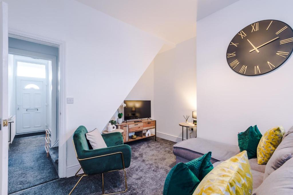 a living room with a clock on the wall at Sleek and Stylish 3 BR Home Mcr in Manchester