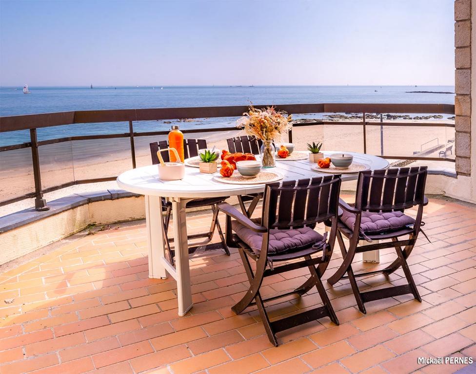 a table with fruits and vegetables on a balcony overlooking the beach at RÉF 318 - LARMOR-PLAGE spacieux type 3 pleine vue mer avec terrasse, ascenseur, parking in Larmor-Plage