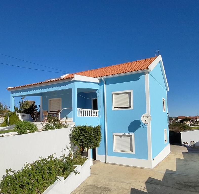 una pequeña casa azul con una pared blanca en Vivenda Palheiras en Roncão