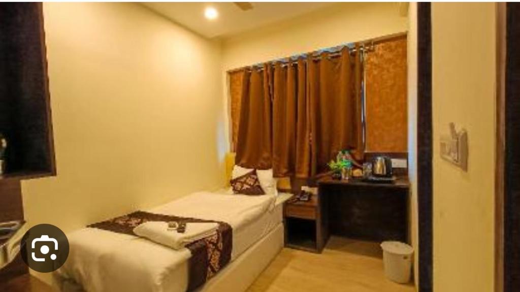 a bedroom with a bed and a desk and a window at HOTEL GINGER GOLD in Pune