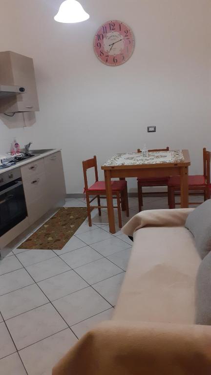 sala de estar con sofá, mesa y reloj en Casa Vacanza Pineta, en Oltrona di San Mamette