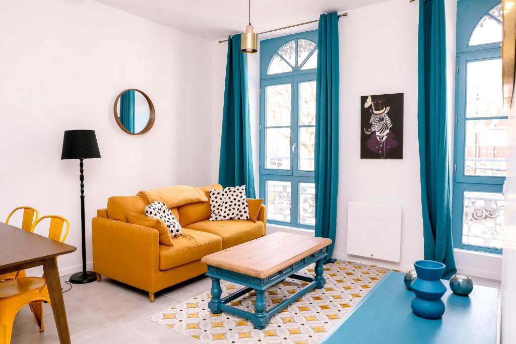 a living room with a yellow couch and a table at Le Jules Appart'Hotel in Romans-sur-Isère