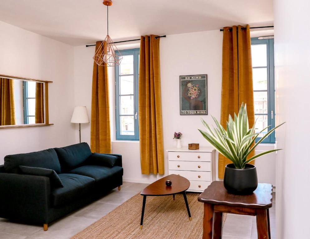 a living room with a couch and a potted plant at Jules Appart'Hotel, Appartements Centre Ville Romans sur Isère in Romans-sur-Isère