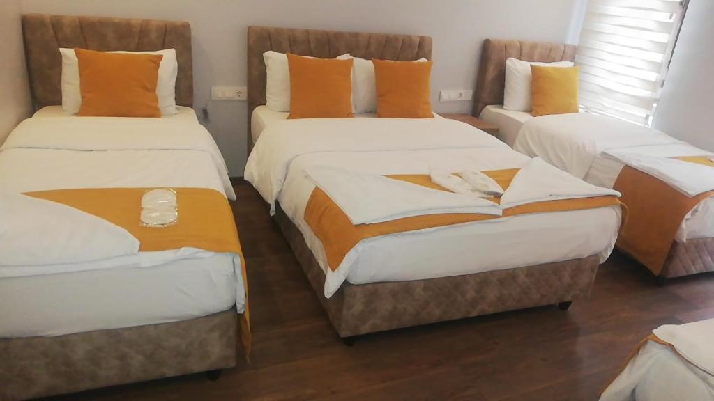 a room with three beds with orange pillows at Mr Lion Kumkapı Otel in Istanbul
