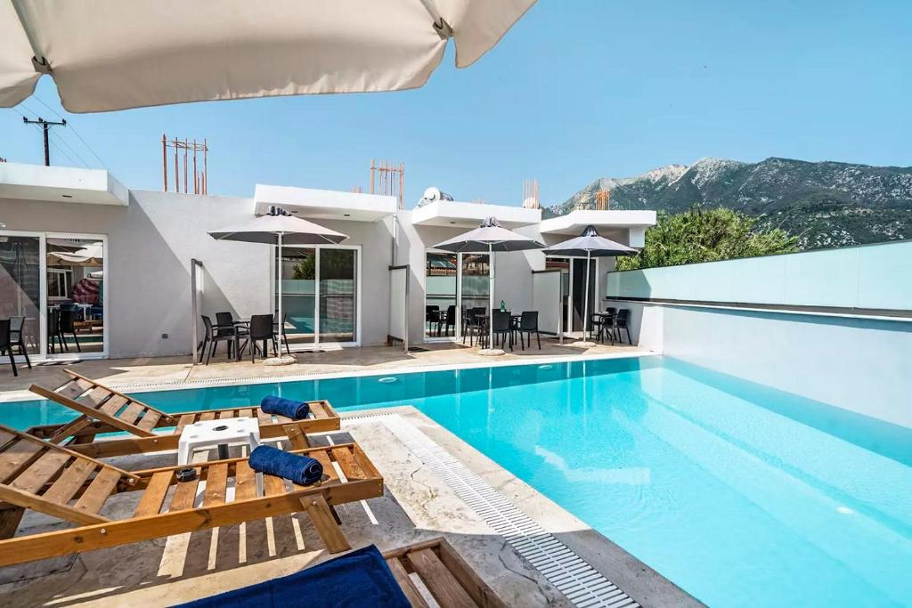 a villa with a swimming pool with chairs and umbrellas at BLUE STAR APARTHOTEL in Nydri