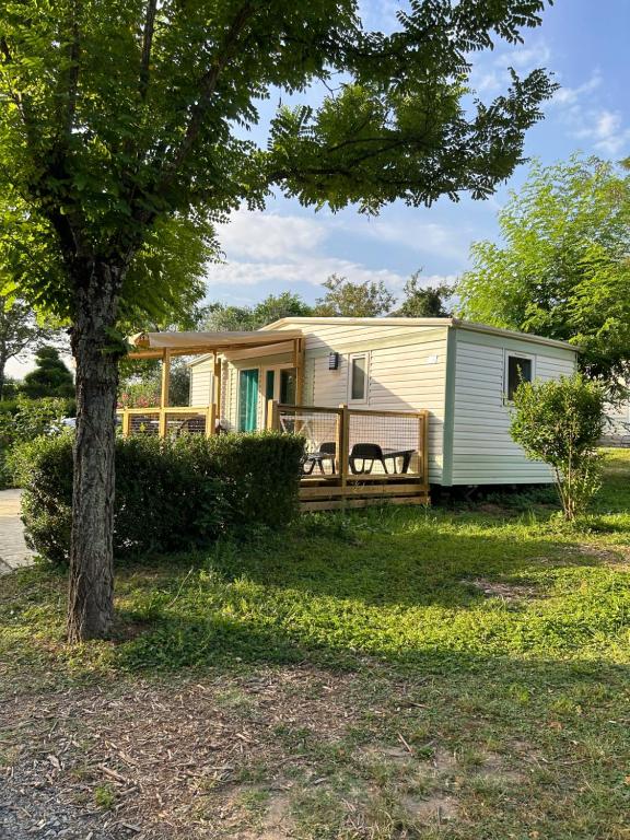 een stacaravan met een terras en een boom bij Camping Beaussement LIBERTY climatisé in Chauzon