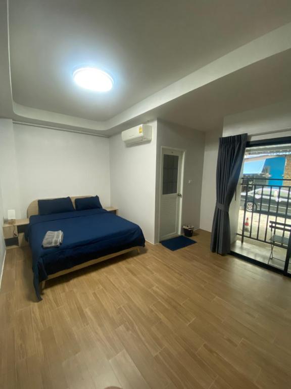 um quarto com uma cama azul e uma grande janela em N place Huei Khwang em Ban Na Song