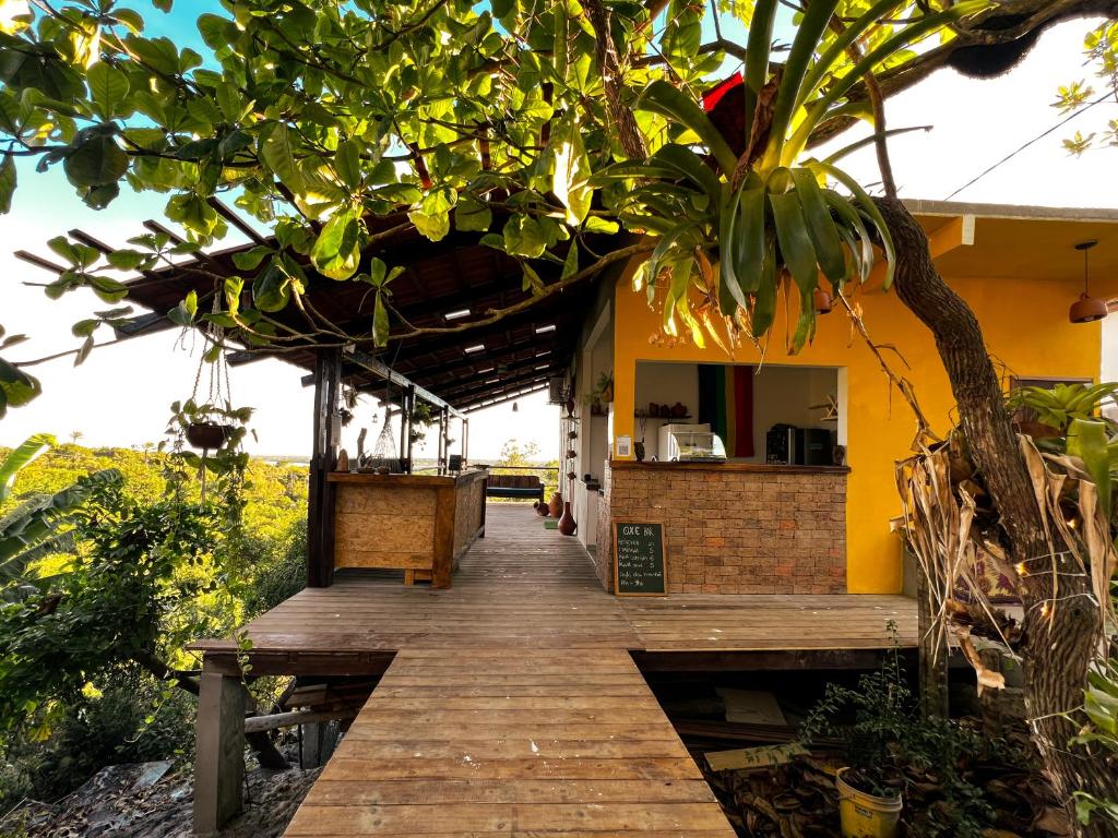 a wooden walkway leading to a restaurant with a tree at OXE hostel in Moreré