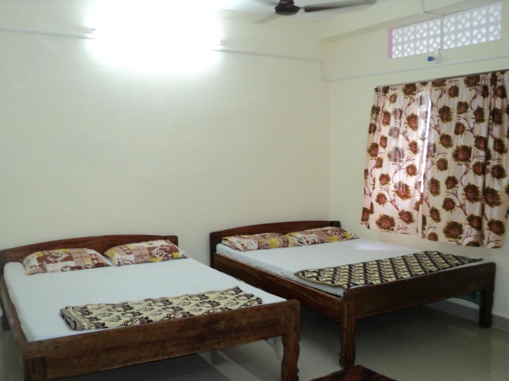 2 camas individuales en una habitación con ventana en Hotel UK Nest en Sabari