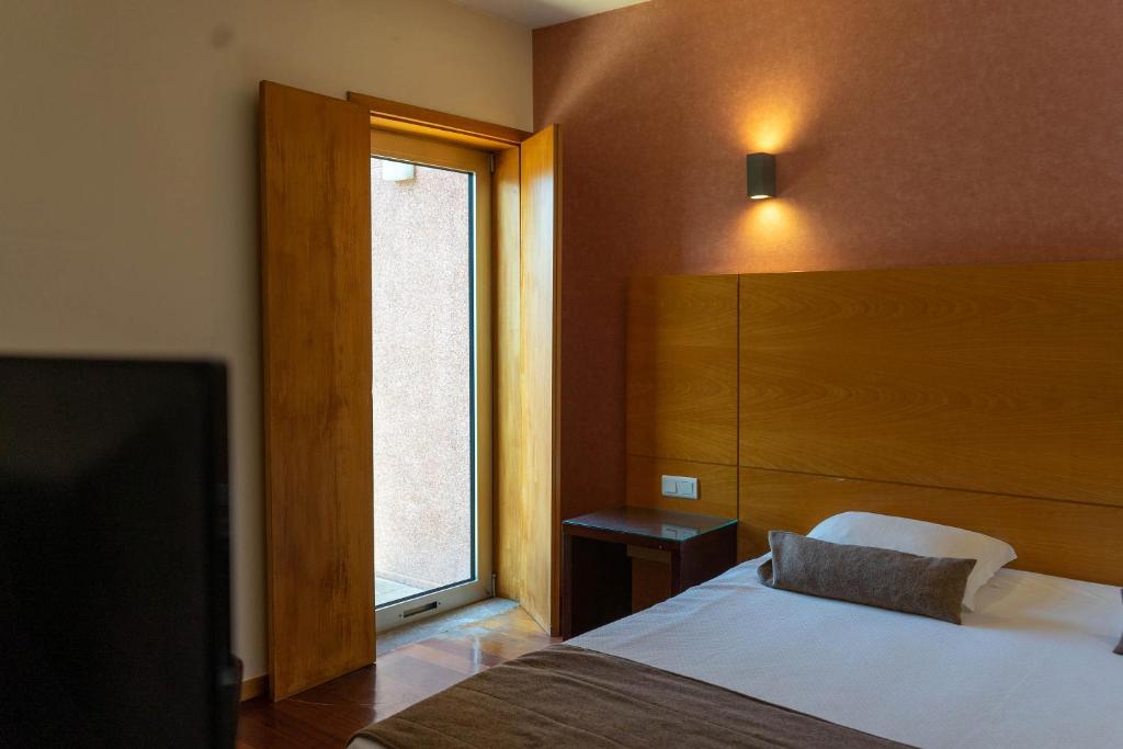 a bedroom with a bed and a large window at Flag Hotel Barcelos in Barcelos