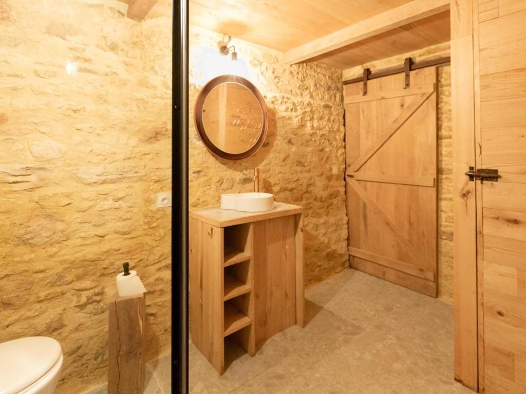 a bathroom with a sink and a toilet and a mirror at Rustic holiday home in Loubejac with jacuzzi in Loubejac