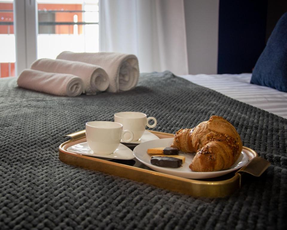 un vassoio con un piatto di pane e tazze su un letto di Doron Living Bari a Bari