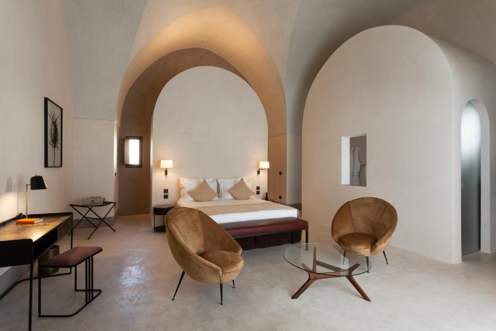 a bedroom with a bed and two chairs and a table at Palazzo Tafuri in Nardò