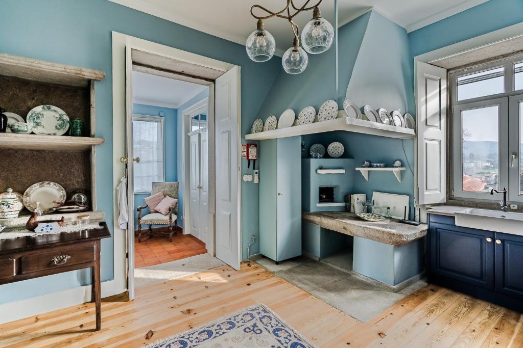 uma cozinha azul com um lavatório e uma janela em Casa da Avó em Caminha