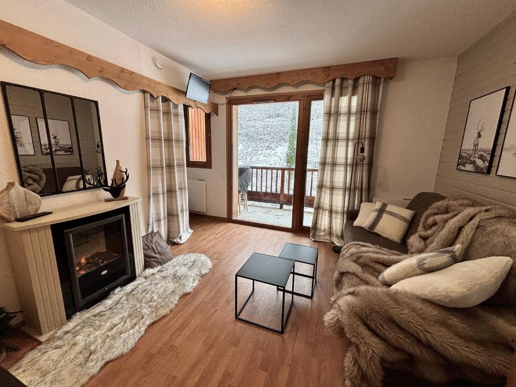 a living room with a couch and a fireplace at Appartement chaleureux au ski avec piscine in Orelle