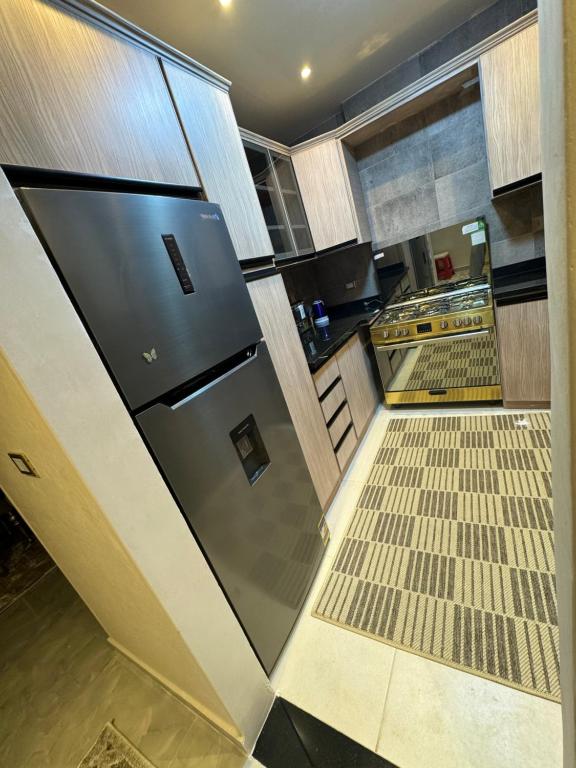 eine Küche mit einem Kühlschrank aus Edelstahl und Fliesenboden in der Unterkunft شارع شومان من الاستاد in Tanta