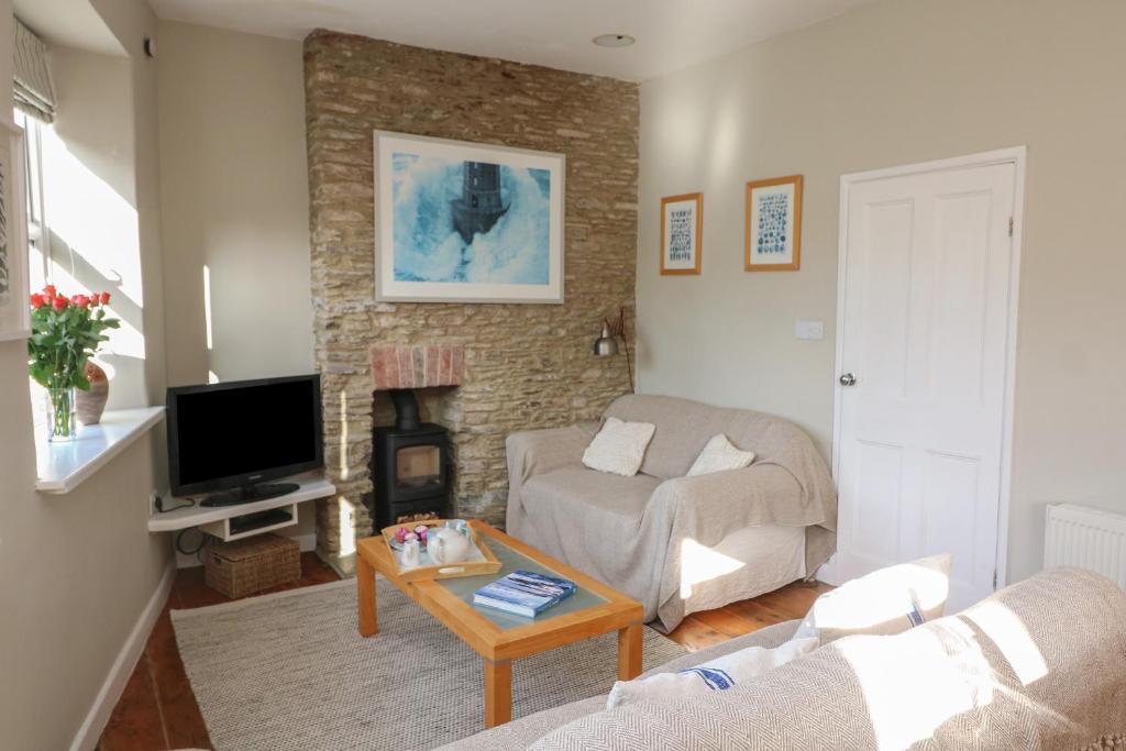 a living room with a couch and a tv at 1 Bailey's Cottage in Dartmouth