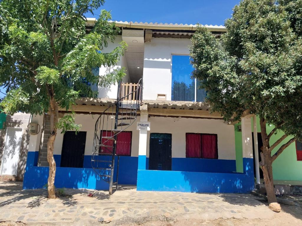 a house with colorful doors and trees in front of it at Emvacamo' in Taganga