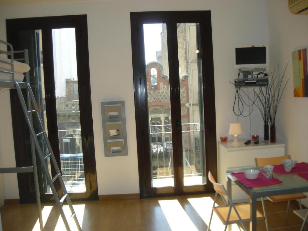 uma sala de estar com uma mesa, cadeiras e janelas em Studio by Sants Market em Barcelona