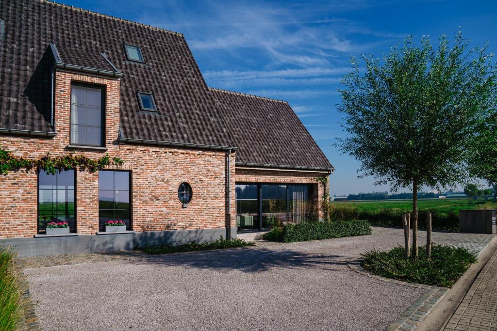 a brick house with a tree in front of it at Vakantiewoning Amico in Gistel